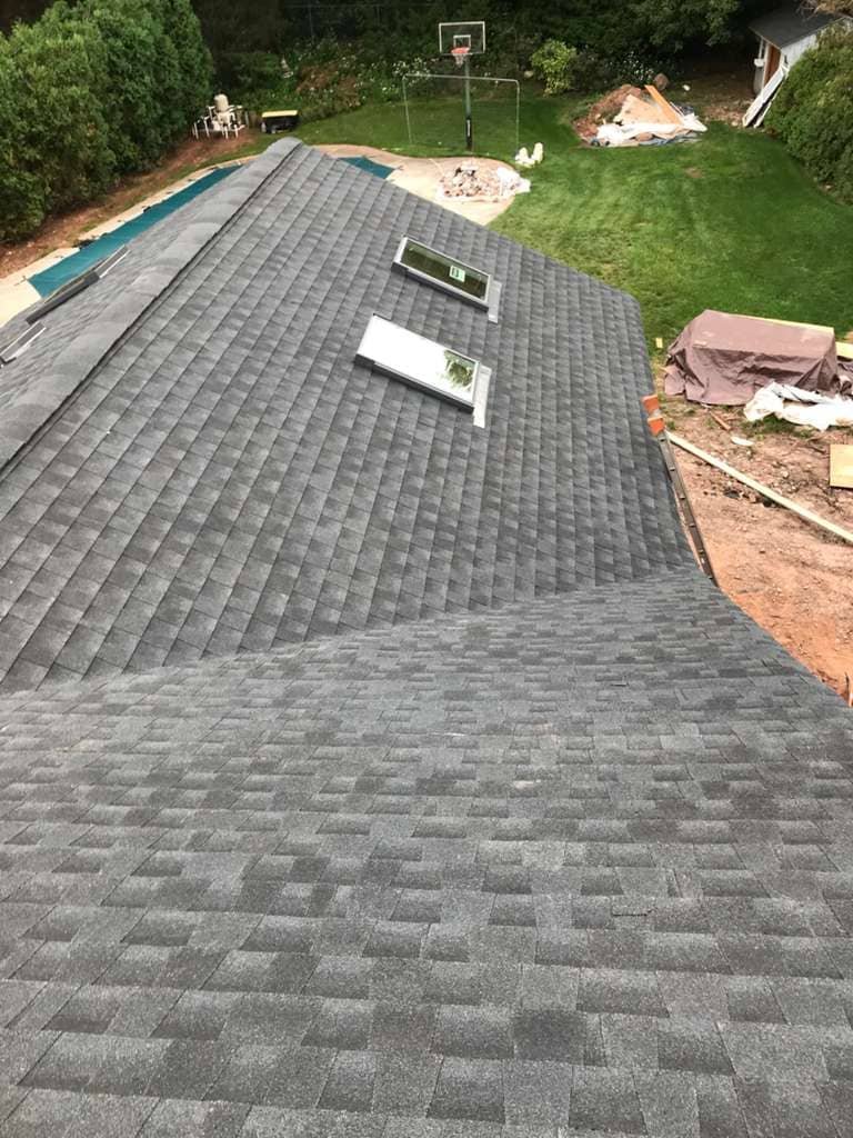 New asphalt shingle roof installation with skylights overlooking backyard and pool area